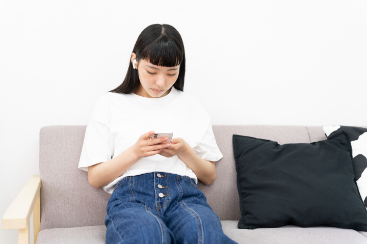 悪い姿勢でスマホを操作する女性