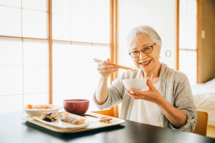 入れ歯を入れて食事を楽しむ高齢女性