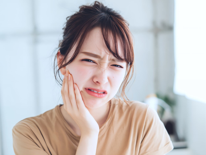 親知らず周辺の歯茎が腫れて痛がる女性