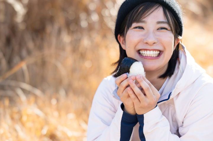 顎の痛みが治って美味しくおにぎりを食べる女性
