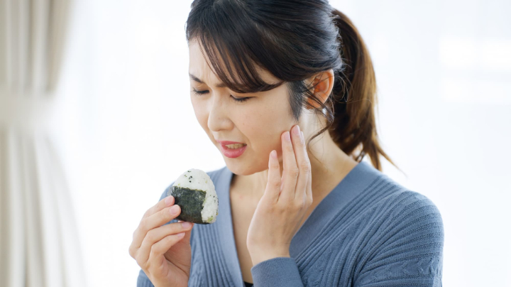 おにぎりを噛むと顎が痛い女性