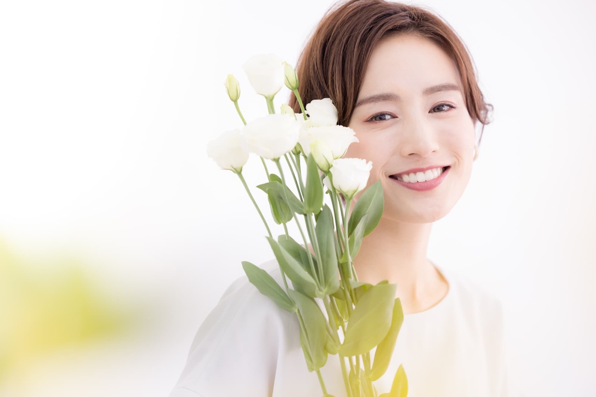 審美歯科で前歯がきれいになった花を抱いた笑顔の女性