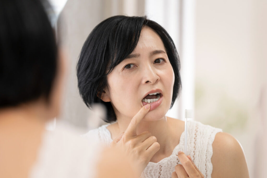 黒ずんだ歯茎を鏡で確認している女性