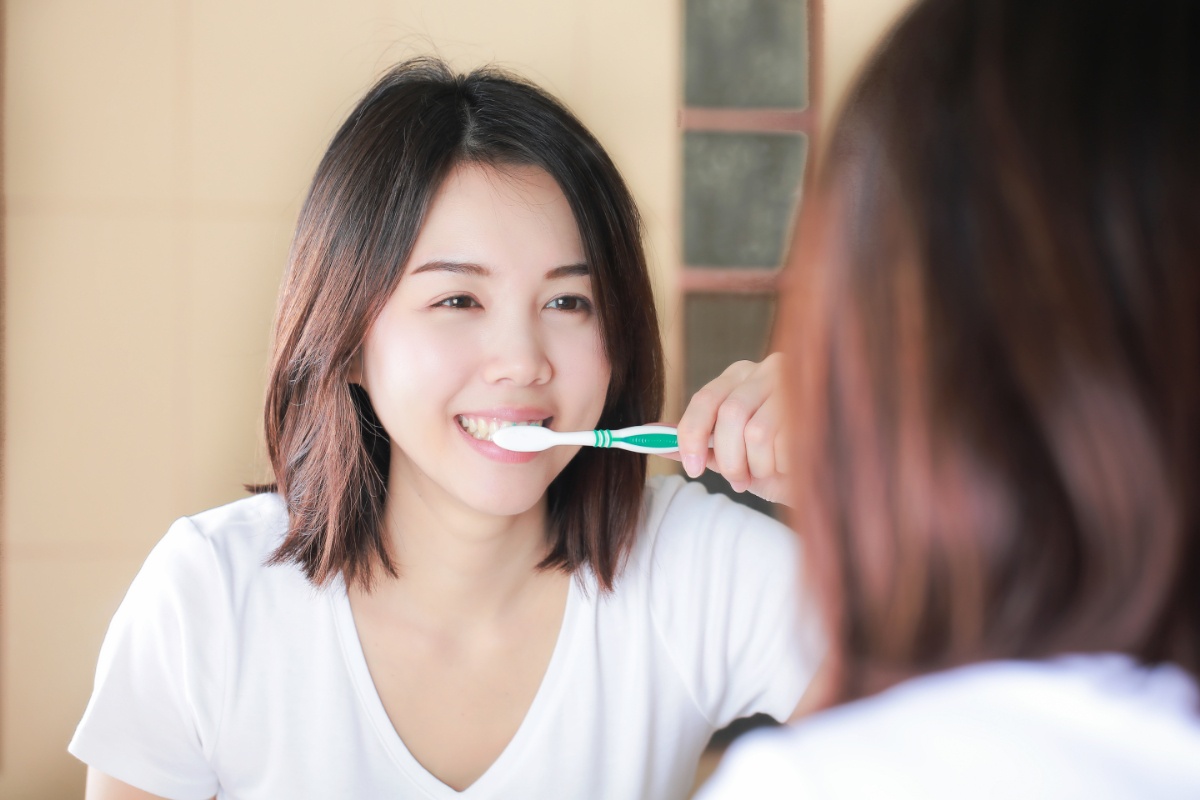 鏡を見ながら丁寧な歯みがきでプラークを落とす女性